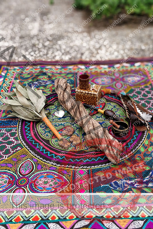 Plant medicine ceremony setting with leaves, roots and other tools on psychedelic blanket on the ground
