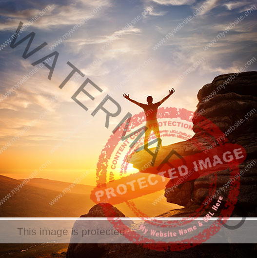 Guy standing on a cliff in front of sunset stretching his hands to the sky