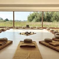 Interior of the ceremony room at the retreat center. Through the large glass wall you have a view of the estate. Inside, the atmosphere is warm, and there are 12 mattresses with meditation cushions on them in a circle.