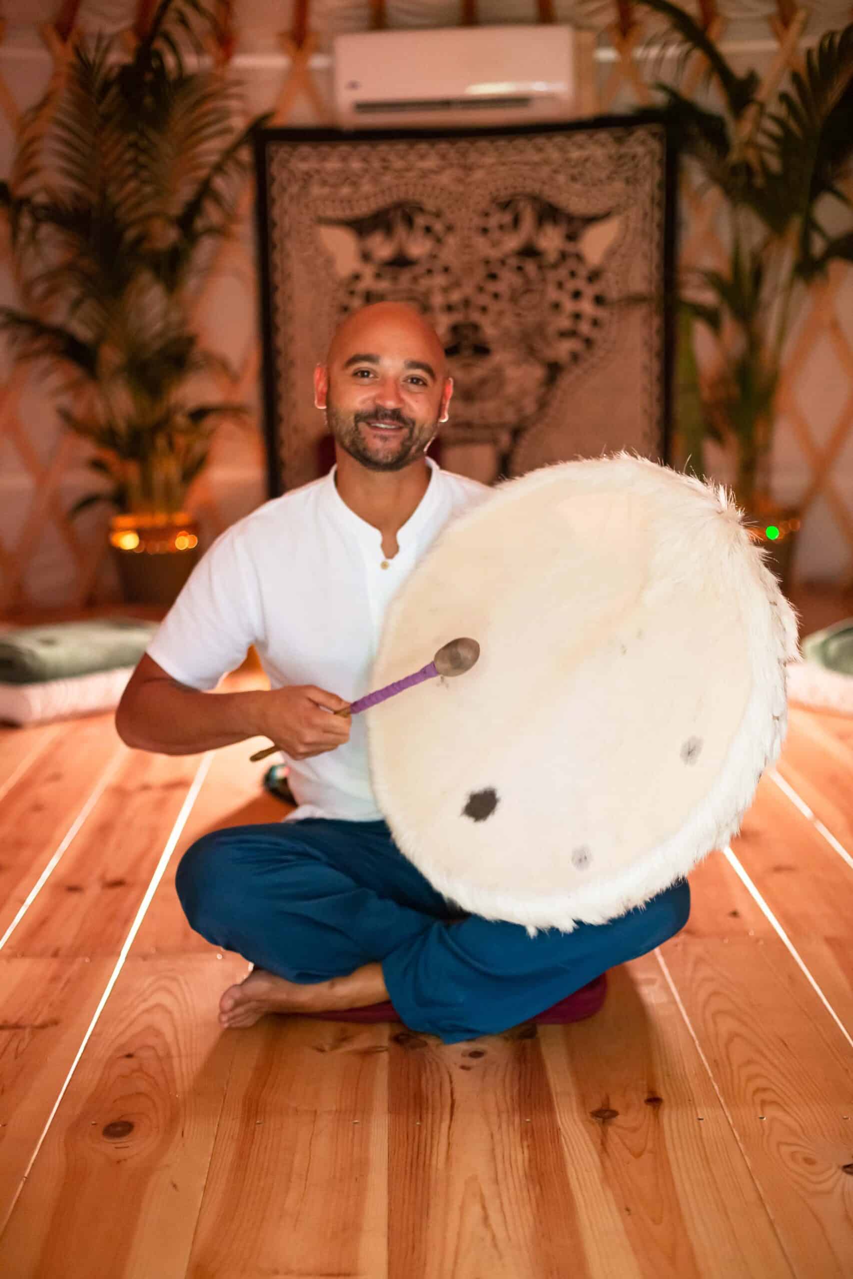 ceremony leader playing a shamanic drum inside a warm lighted ceremony room