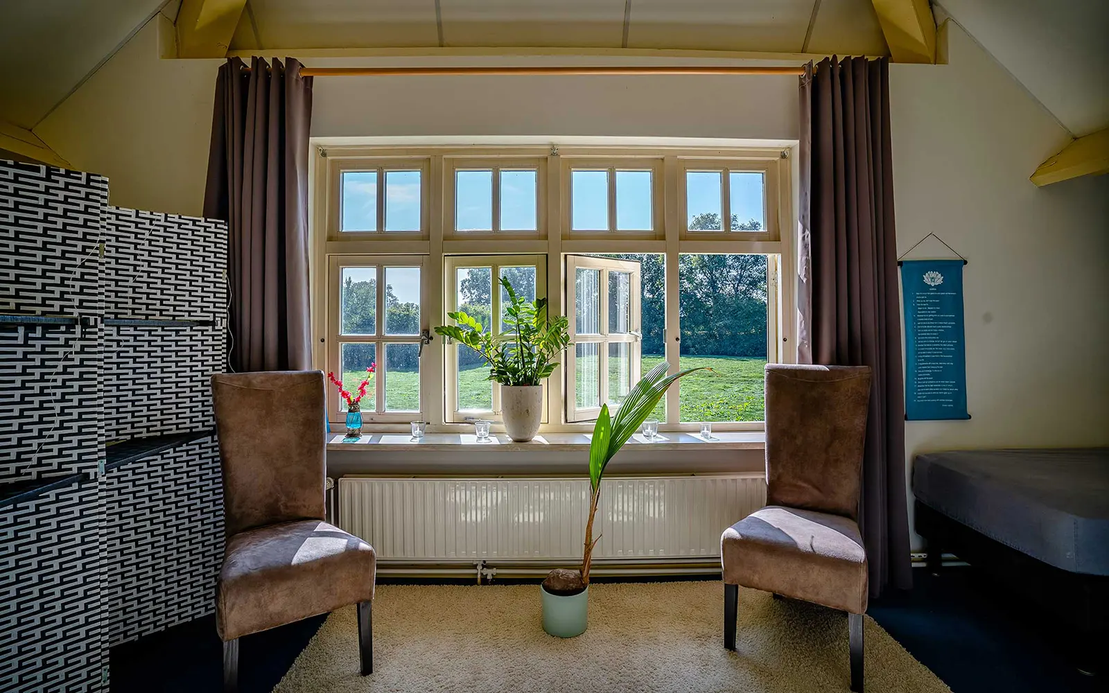 Bedroom with two chairs in front of windows on sunny day