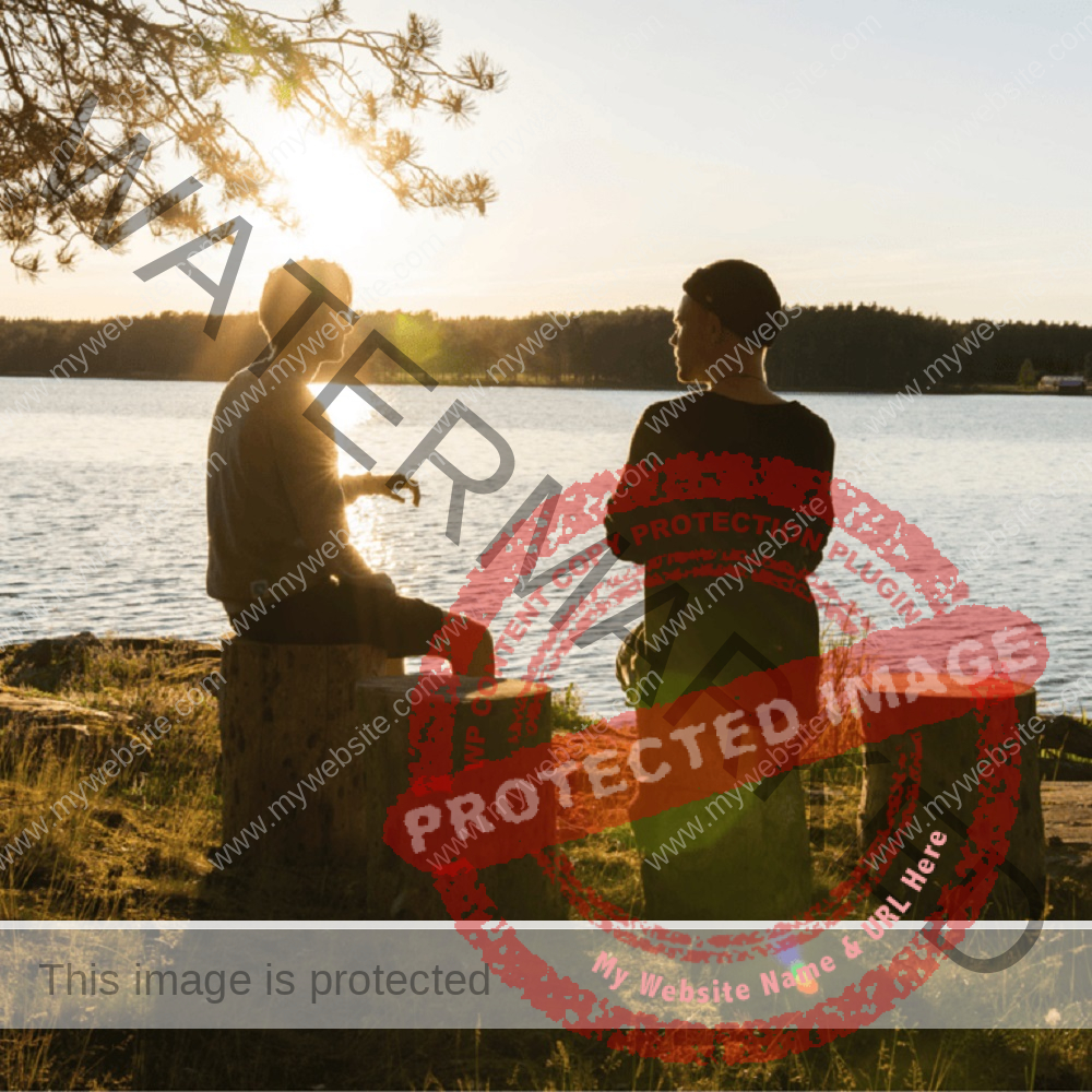 Two guys sitting on wood next to a sea and talking while sun shines