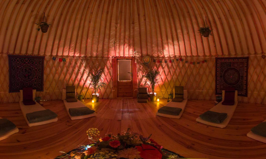 Retreat ceremony room with warm light, mattresses and meditation seats