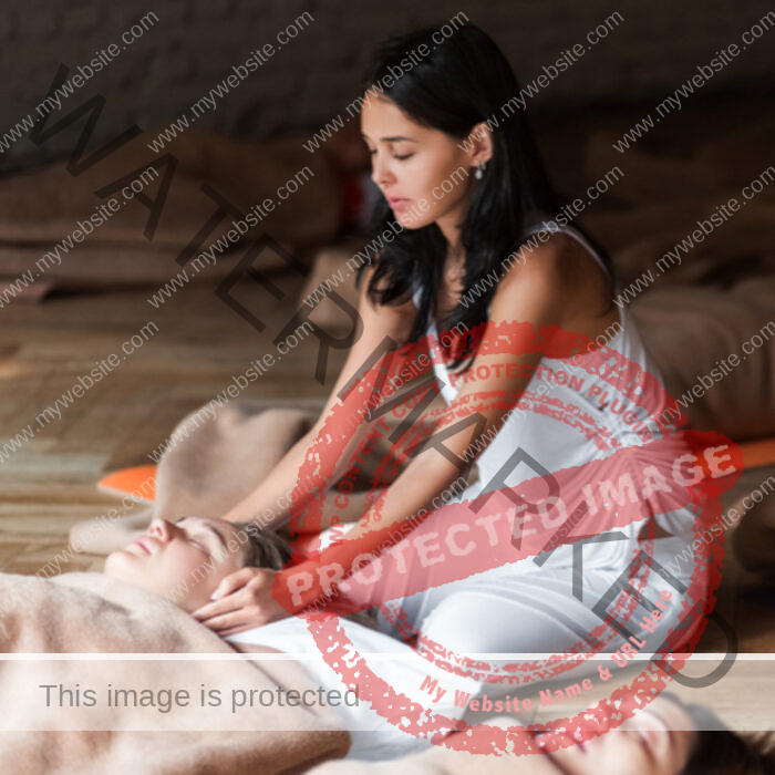 Black haired young woman holding her hands on ears of laying woman