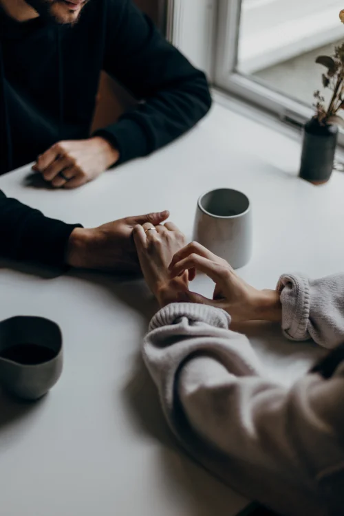 Man and woman holding hands at table