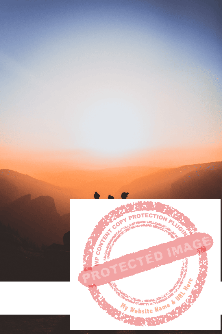 Three people standing on mountain while sun rises