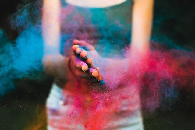 Woman clapping hands, colorful powder in the air