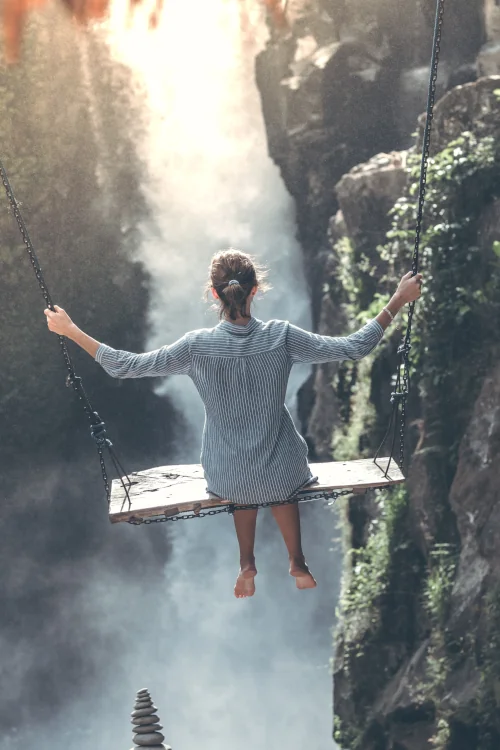 Woman on swing, huge waterfall and nature in the background