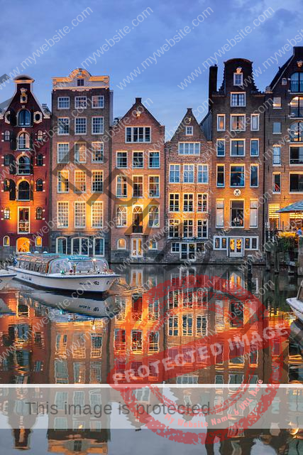 a row of traditional Dutch buildings at twilight reflecting on a still canal