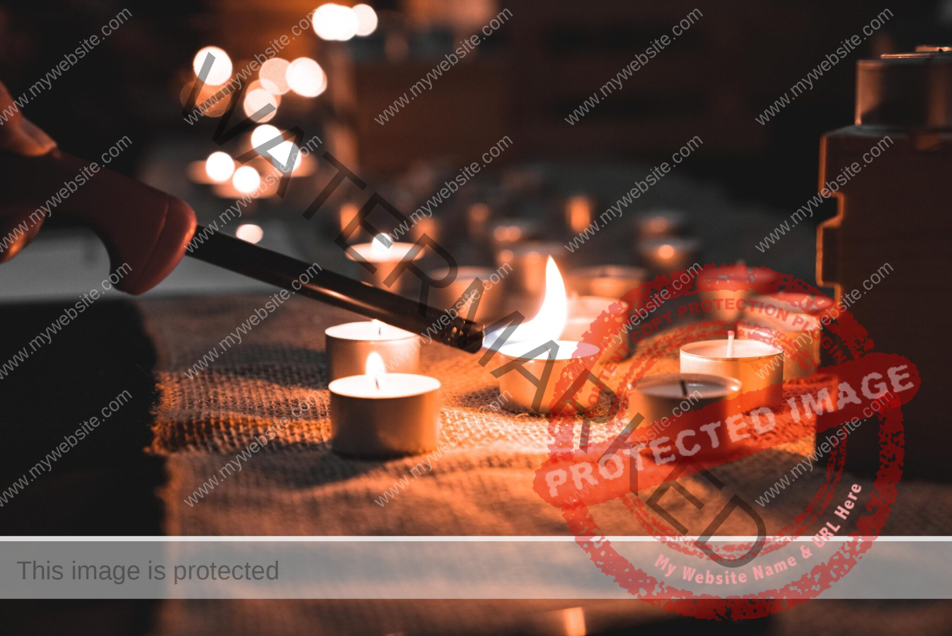 hand lighting a candle on a table with many other candles lit