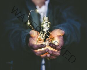 man in a suit holing a light bulb with fairy lights insight