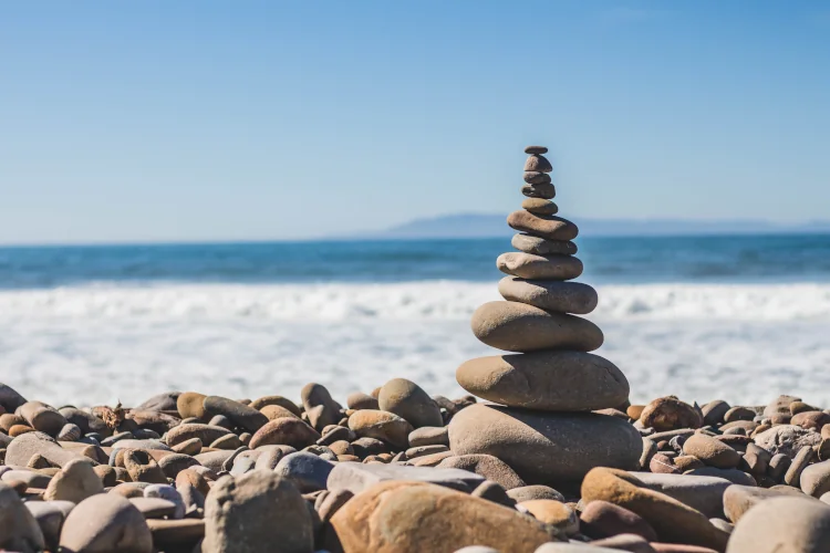 Cairn on stony beach, ocean and blue sky in the background