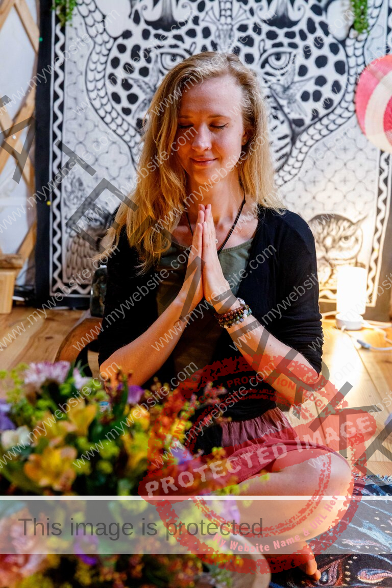 Young woman praying in Yurt in front of flowers
