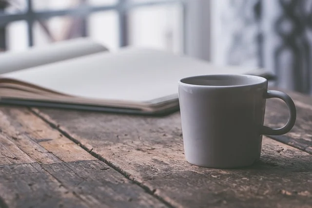 Tea cup on wooden table, journal behind it