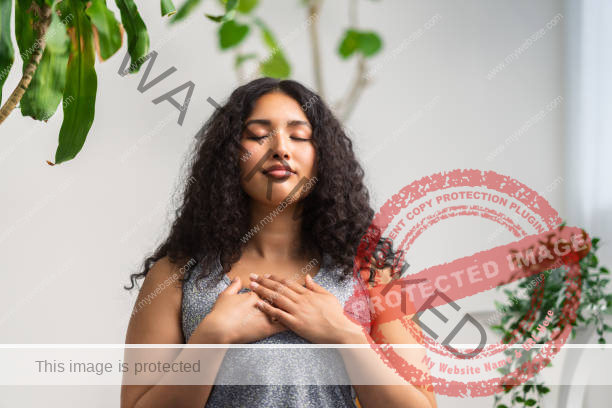 woman sitting with her eyes closed and her hands over her heart