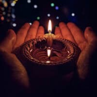 Lighted Candle holded in hands, stars in the background