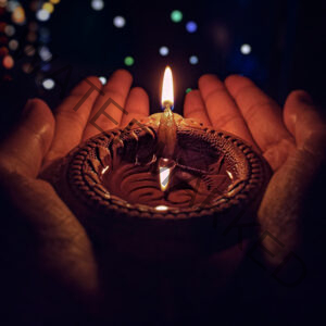 Lighted Candle holded in hands, stars in the background