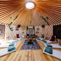 Yurte with mattresses, meditation seats, blankets and sun shining through sealing window