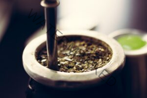 crushed herbs in mortal and pestle container with a blurred background 