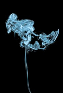 blue white smoke on a black background making abstract shapes 