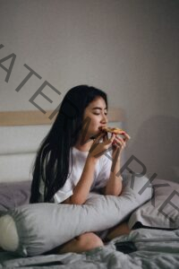 woman sitting on her bed eating