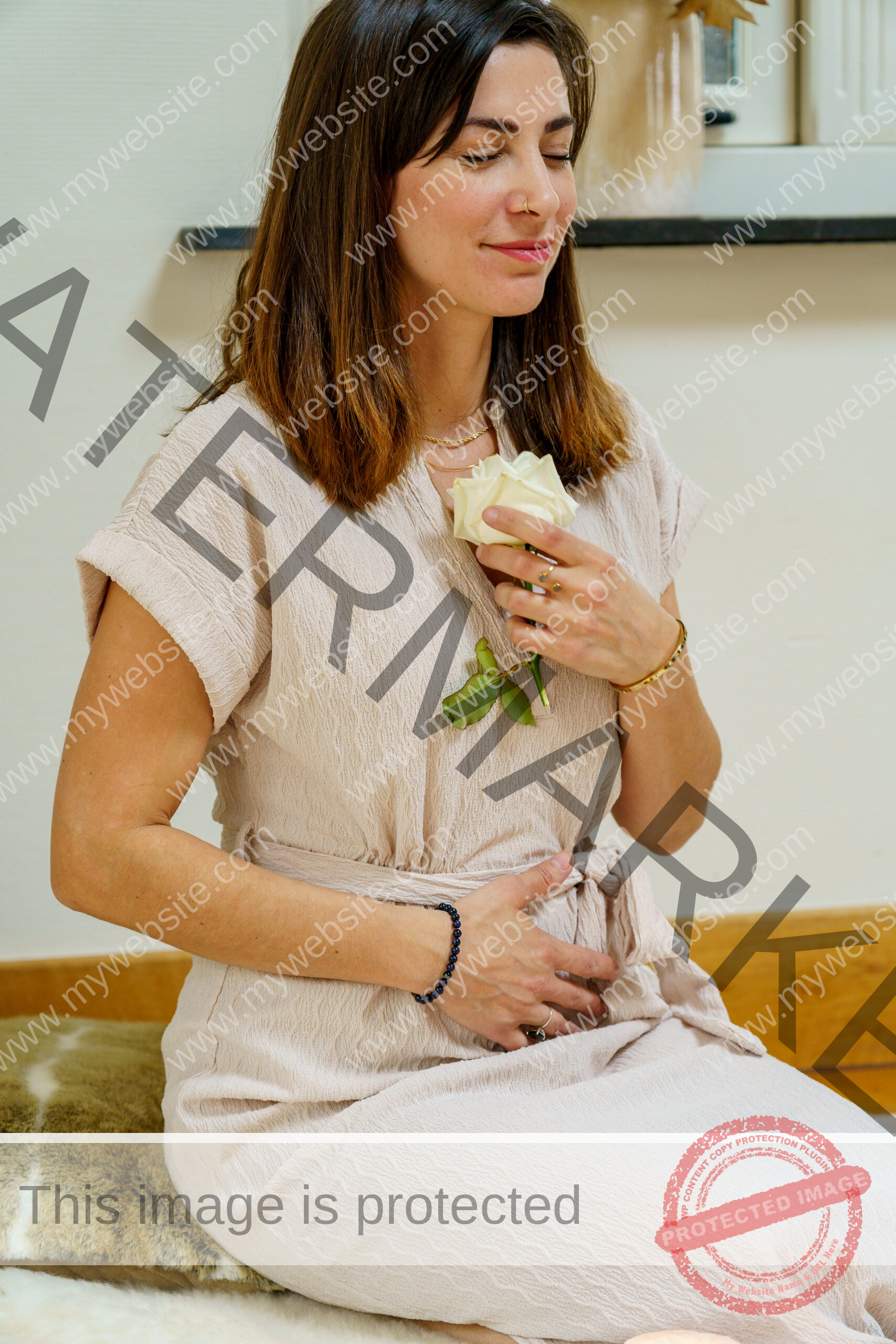 Young Woman with brown hair, closed eyes holding a white rose to her chest smiling