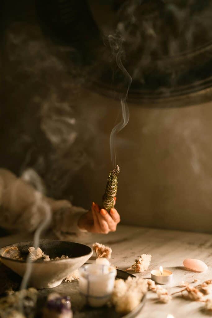 Female hand holding burning incense in her left hand, smoke is filling the room