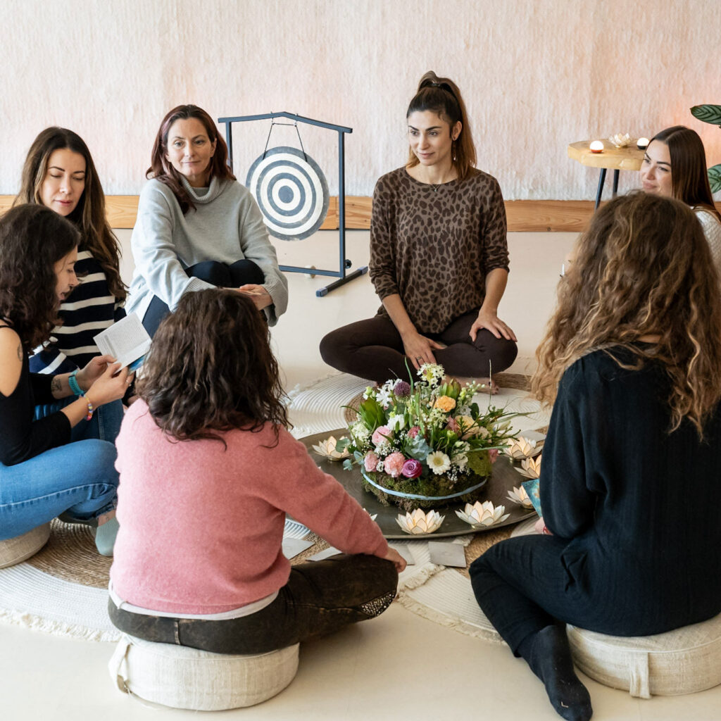 Retreat participants seated in a circle inside a warmly lit room, engaging in a group session