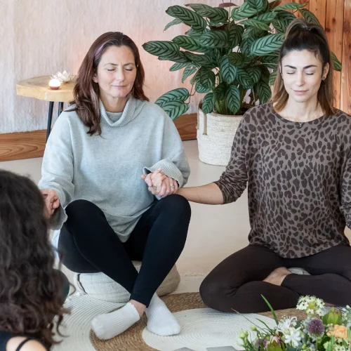 Women meditating in a circle and holding hands