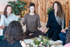 Retreat participants seated in a circle inside a warmly lit room, engaging in a group session