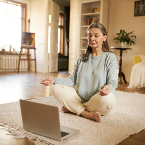 Senior female doing meditation in front of notebook