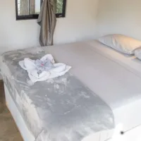 Double bed with white bed sheets in private bungalow
