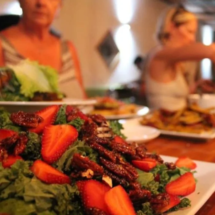 Salade with strawberries on a wooden table, people eating in the background