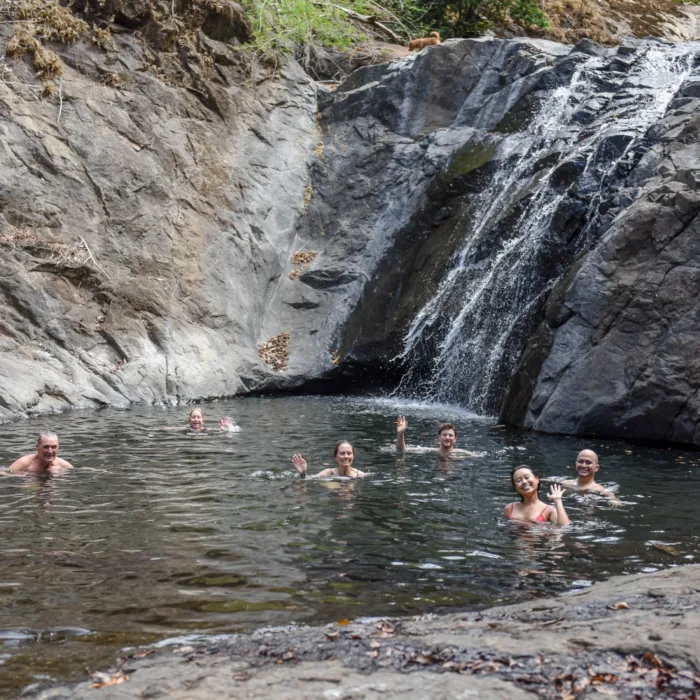 Waterfall with 6 people swimming in front of it