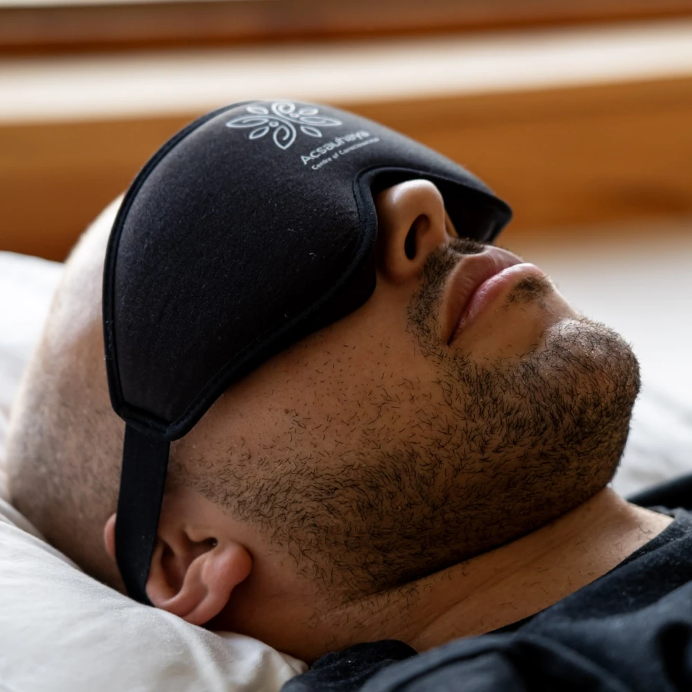 Young guy with black blindfold laying on white pillow, side view