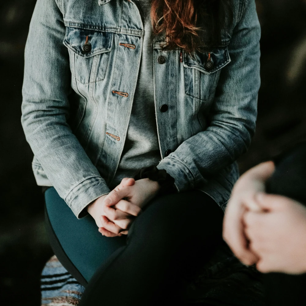 Two people sitting next to each other, hands together